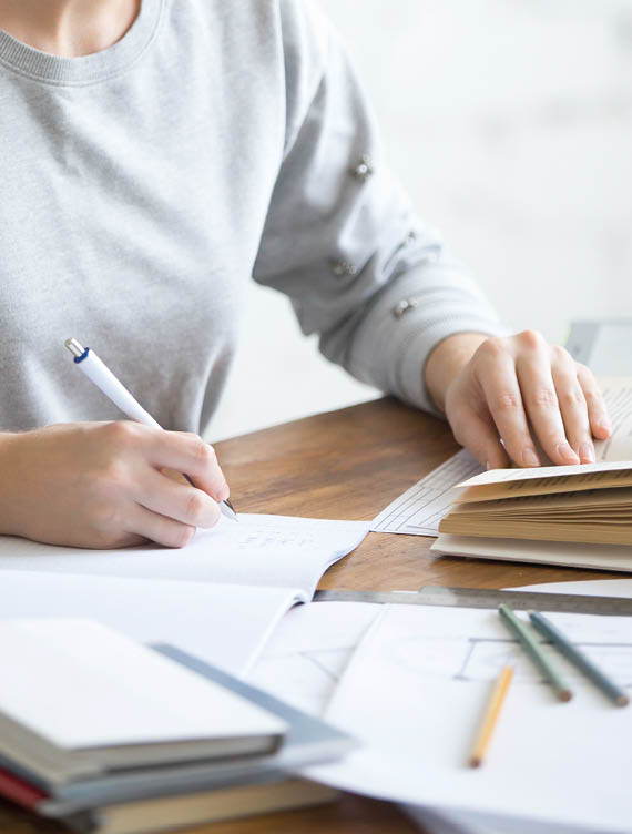 Profile portrait of a student girl performing a written task in a copybook, looking at the textbook, education concept photo