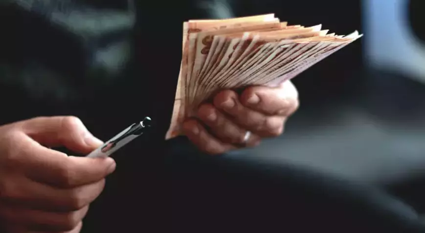 A person holding a stack of money. Description generated by AI