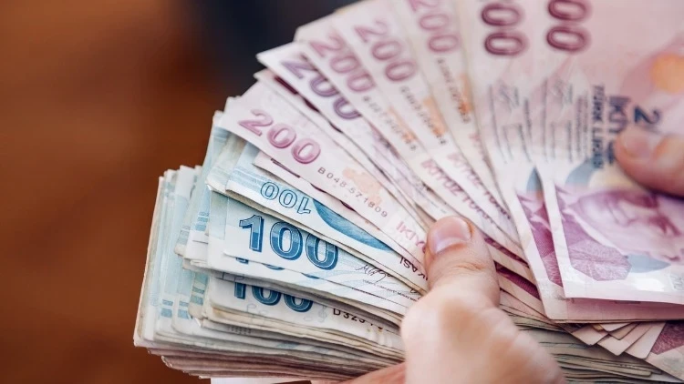 Hands holding a fanned-out stack of various denominations of currency notes. Description generated by AI