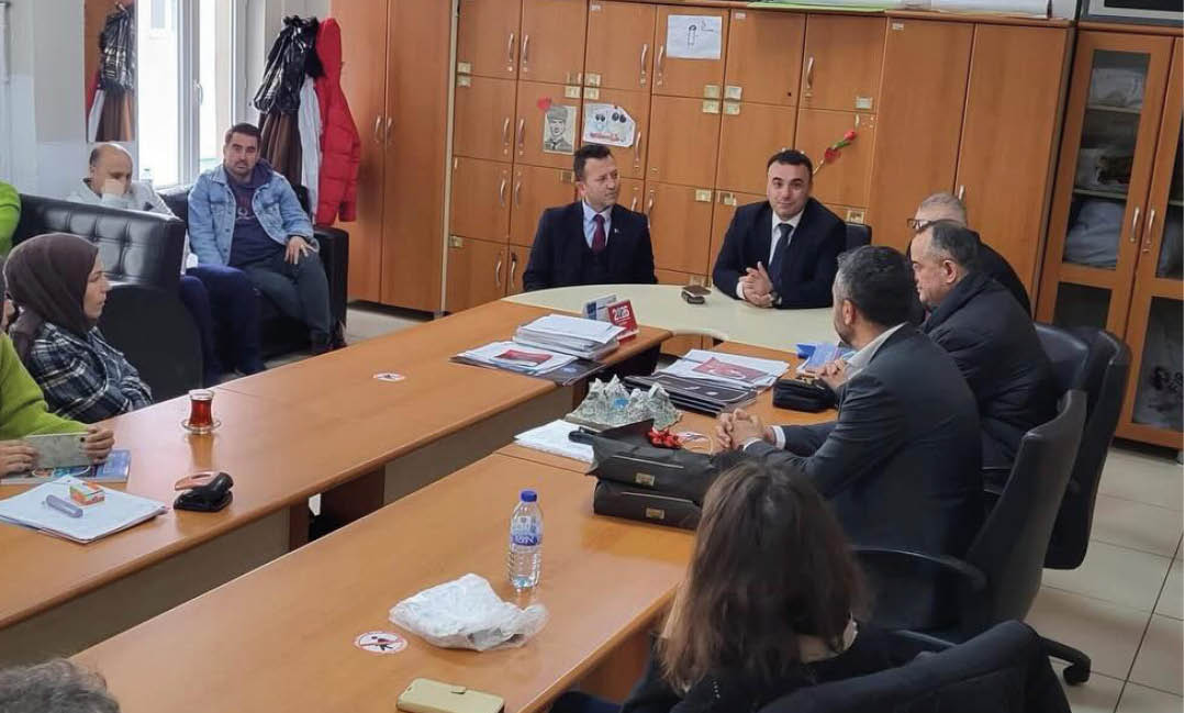 People in business attire are seated around a conference table in an office setting engaged in a meeting. Description generated by AI