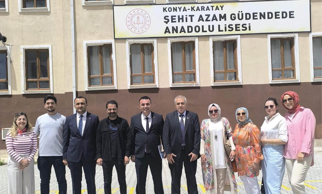 A group of people dressed in formal and casual clothing stand side by side outdoors in front of a building with windows and a sign above. Description generated by AI