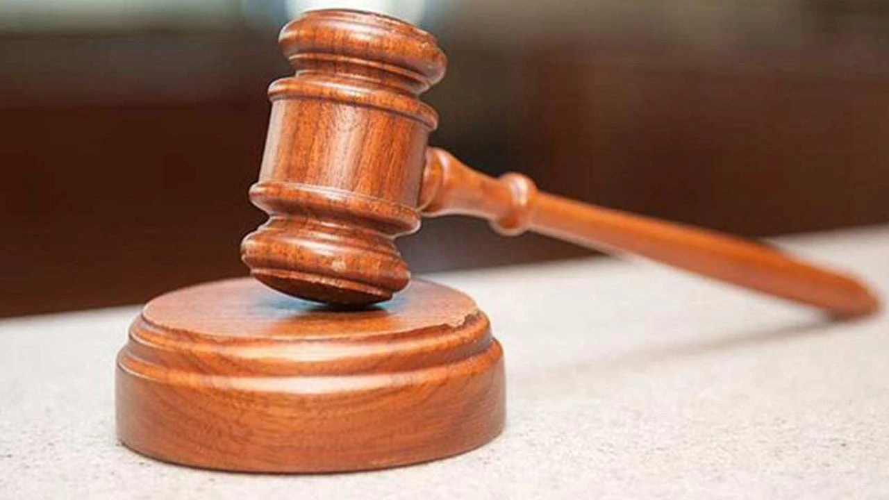 A wooden judge's gavel resting on a matching sound block on a light-colored surface. Description generated by AI