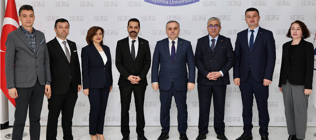 Five adults dressed in formal business attire stand side by side against a plain backdrop with a repeated logo pattern. Description generated by AI