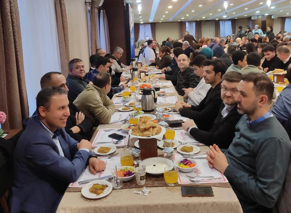 A group of people are sitting around a table with plates of food. Description generated by AI