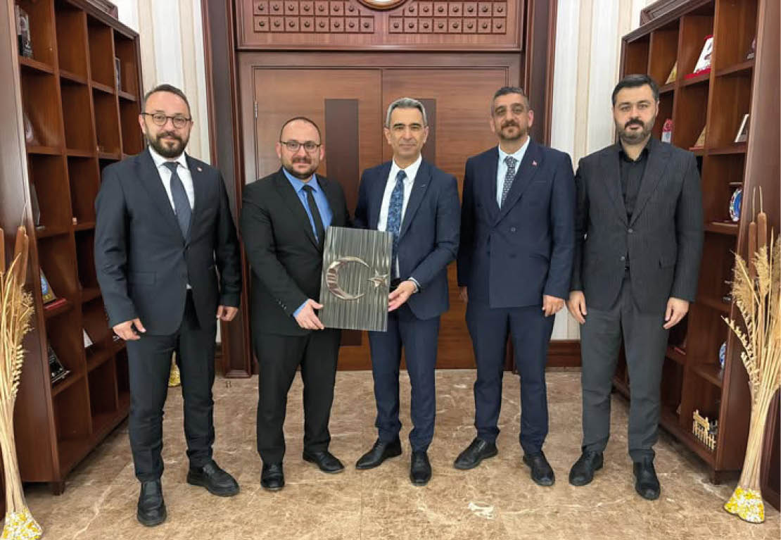 A group of men in suits holding a book. Description generated by AI