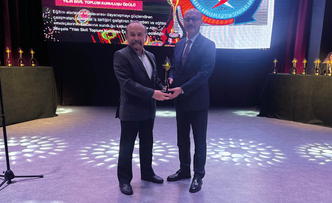 Two men standing on a stage holding an award. Description generated by AI