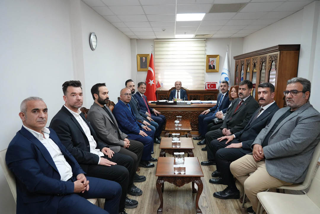 A group of men wearing suits and ties sitting around a table. Description generated by AI