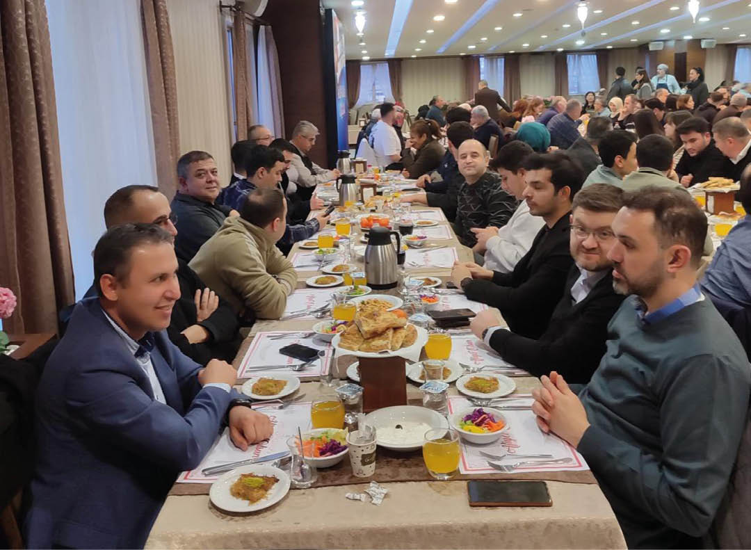 A group of people are sitting around a table with plates of food. Description generated by AI