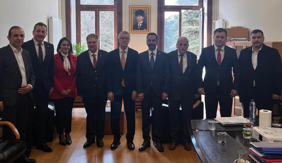 A group of men wearing suits and ties standing in a room. Description generated by AI